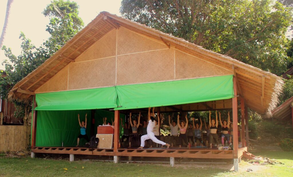 people practicing yoga in a nipa hut