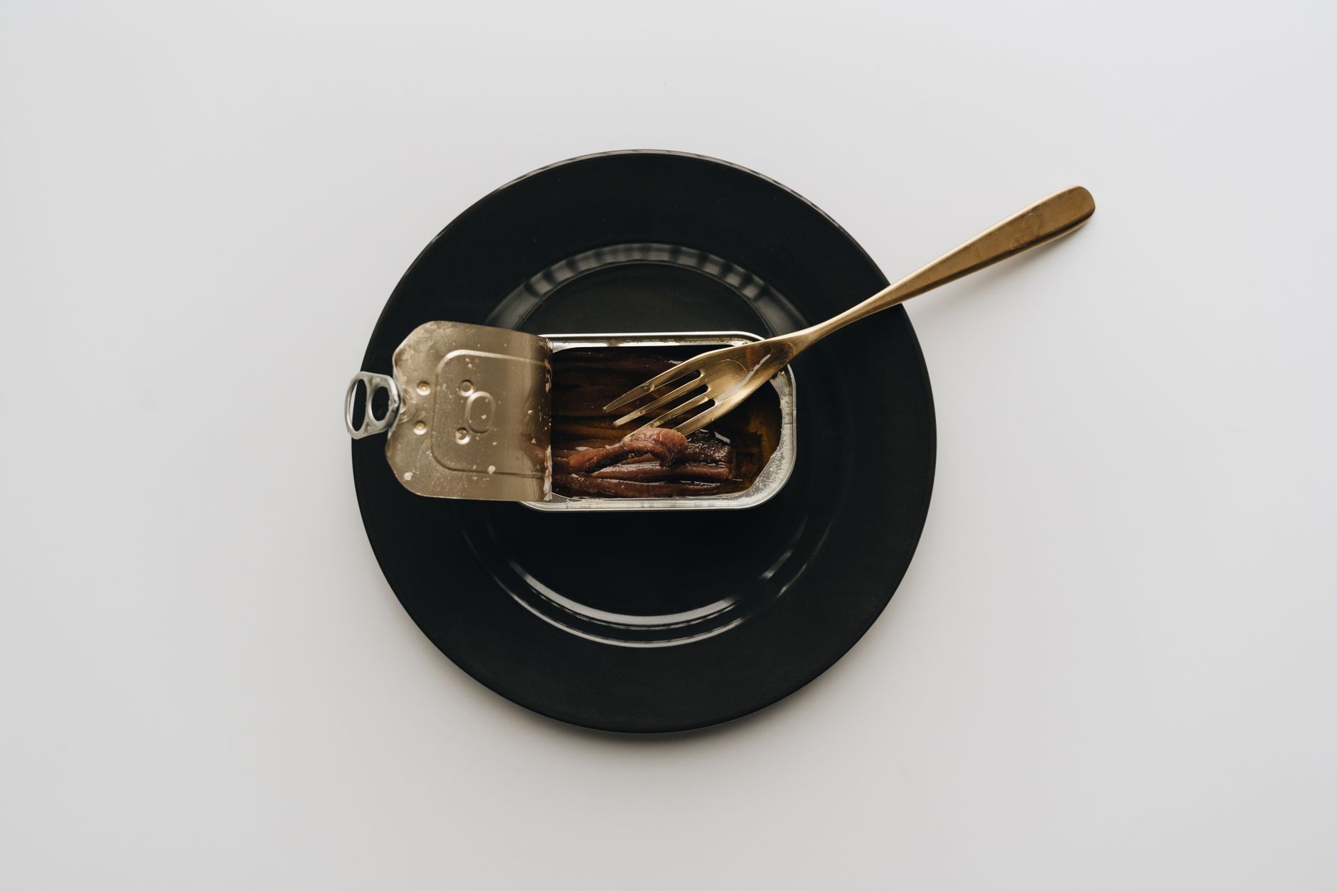 a fork in a can of anchovies