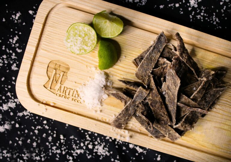 slices of meat o a wooden chopping board with lime and salt
